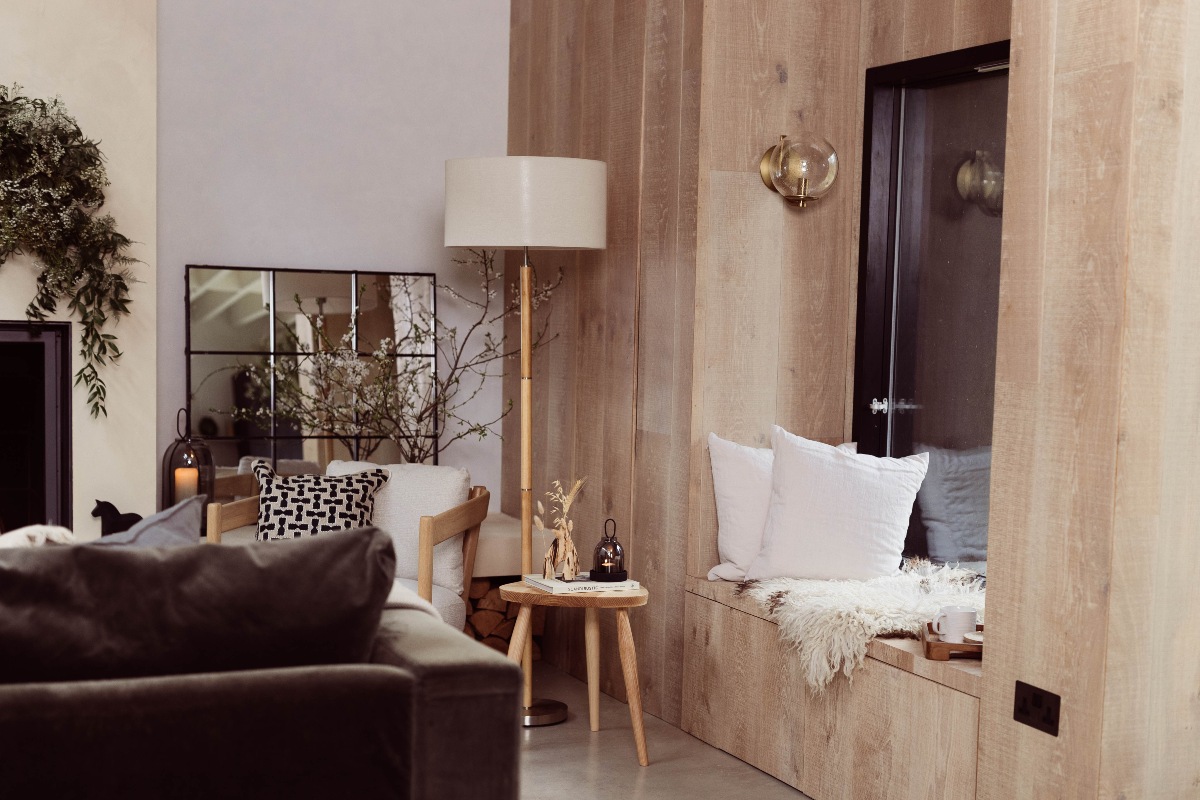 A Scandi style living area with a window nook, faux fur furnishings, wood panelling and neutral decor.