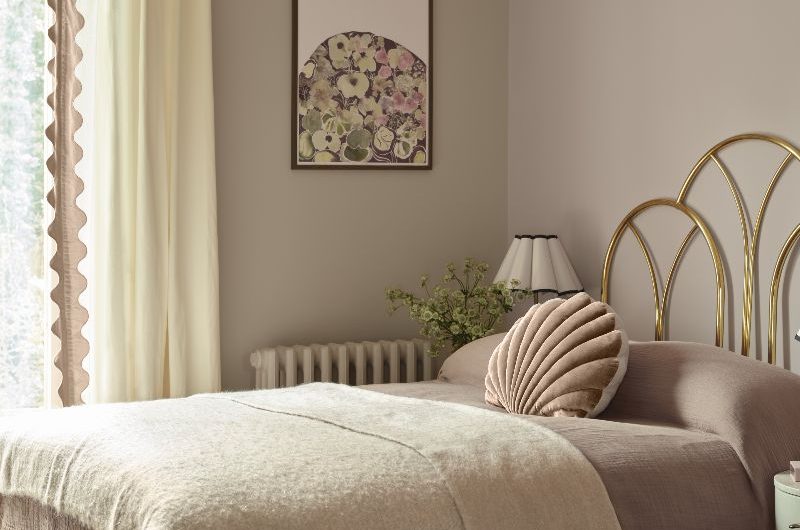 Calm bedroom design with neutral shades, a gold metal bed frame, and layered textures.
