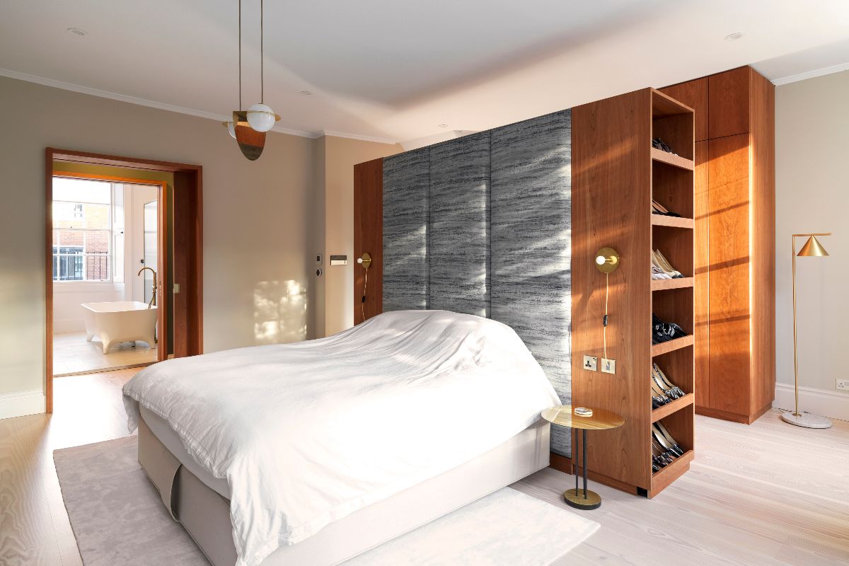 A master suite with an in-room walk-in dressing area, custom built from cherry wood, with the other side acting as a statement headboard.