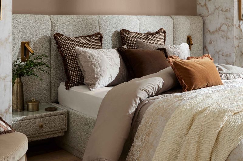Neutral bedroom design with a boucle bed frame with built-in bedside tables and a mix of layers on the bed.