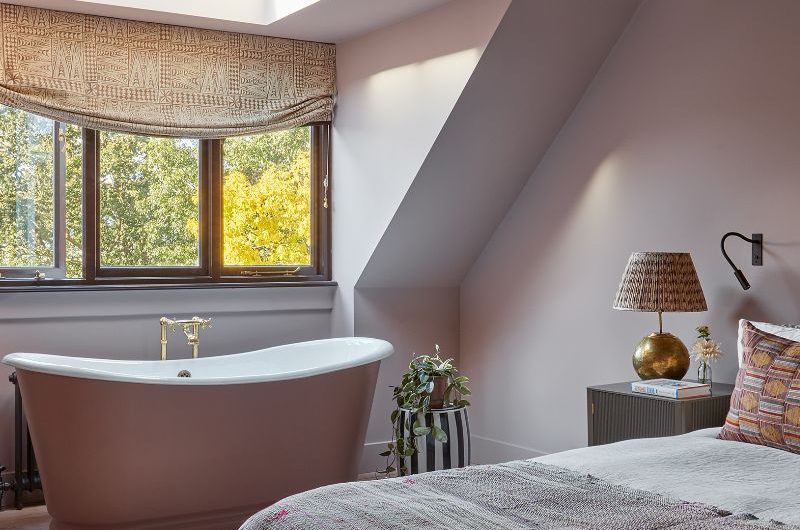 Open-plan bedroom with a freestanding tub near the window.