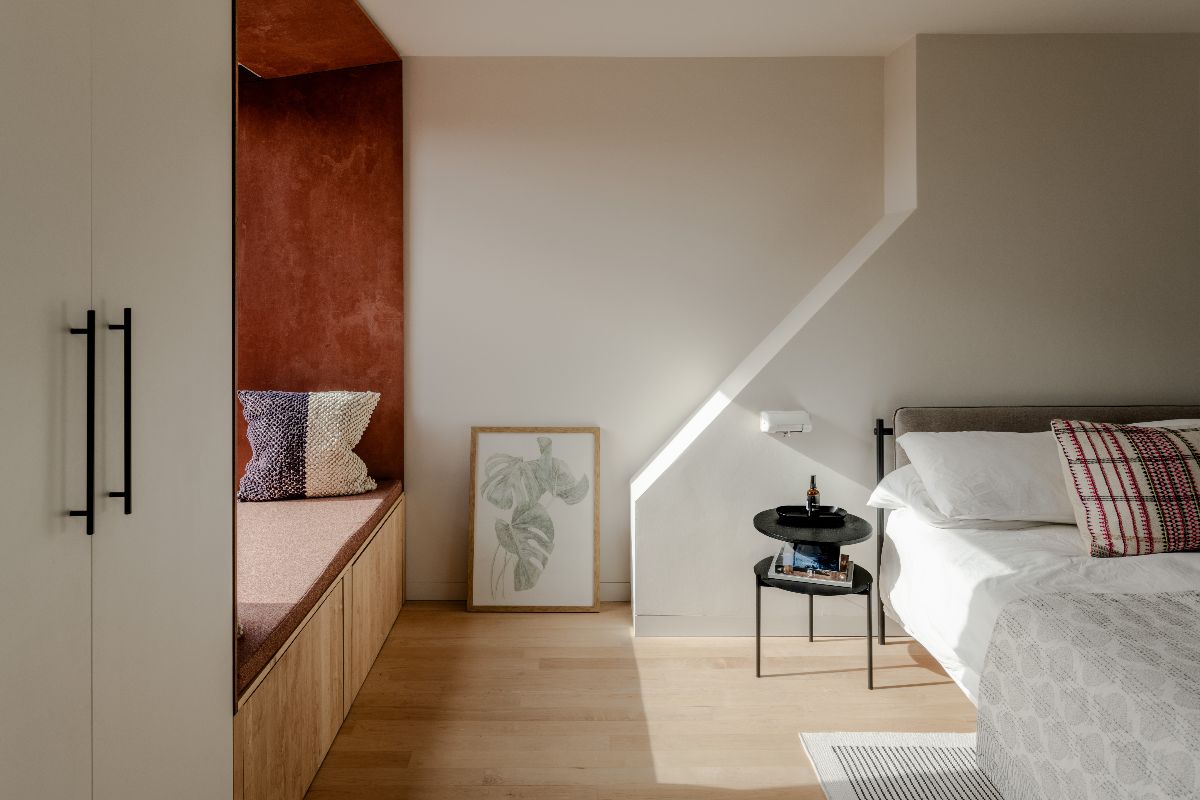 A medium sized bedroom with bespoke fitted wardrobes, a custom window seat and a low platform bed.