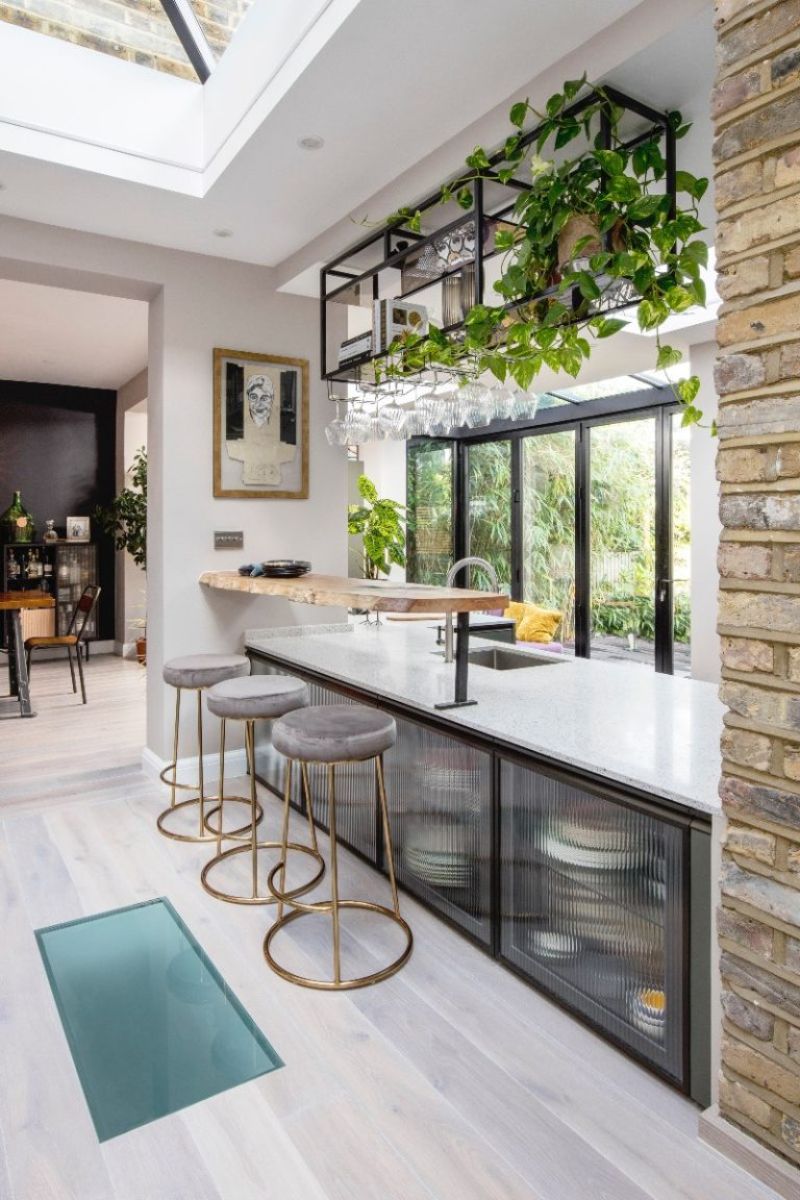 A breakfast bar area made from wood with a shelving unit above it and reeded cabinets below.