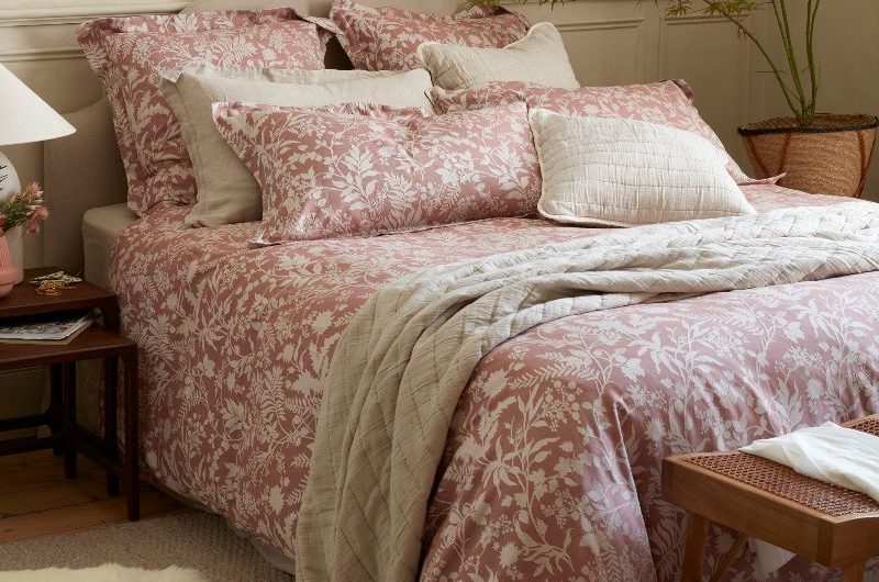 A calm bedroom design with neutral paint, natural textures, floral bedding and textured rug.