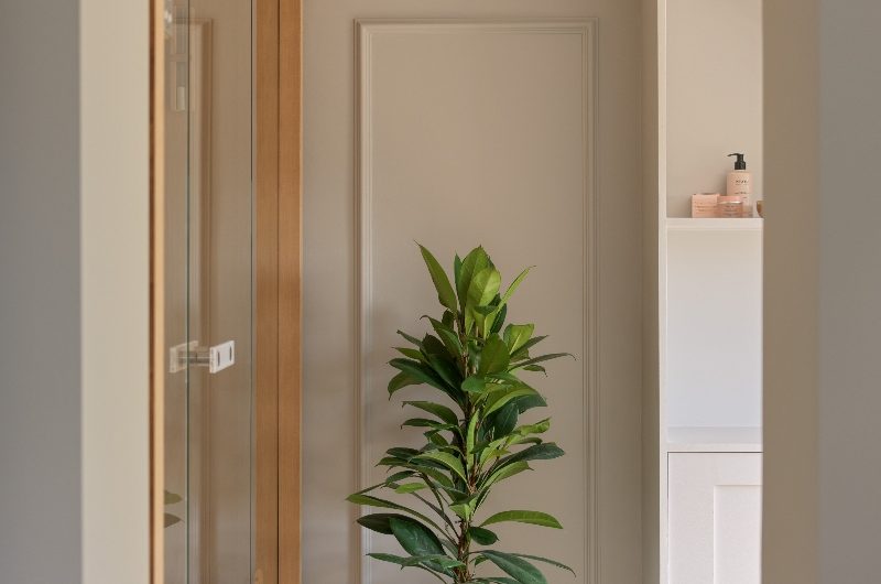 A neutral scheme with wall panelling, parquet flooring, a sauna, and house plants.
