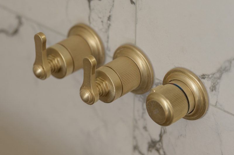 Closeup at the brassware mounted on veiny marble-effect surfaces.