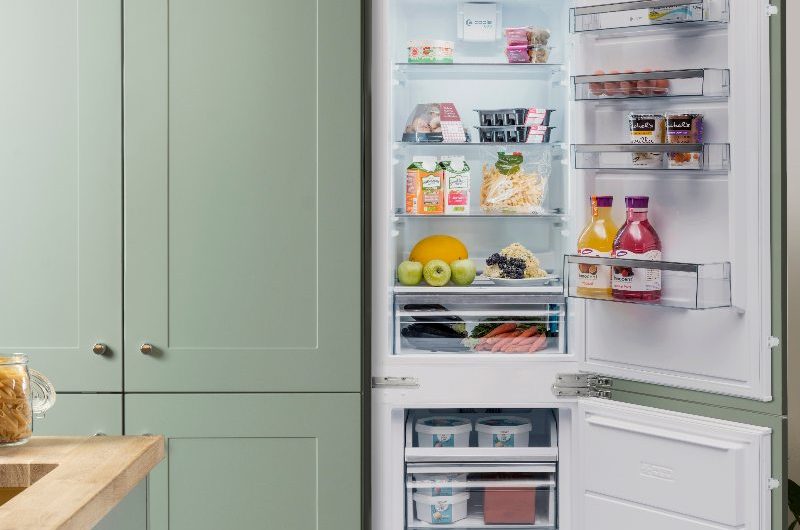 Classic cabinetry painted in green with an integrated fridge-freezer.