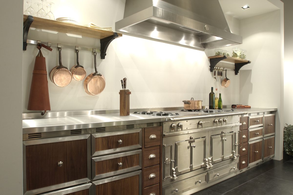 An industrial style kitchen with stainless steel range cooker, extractor and work surfaces.