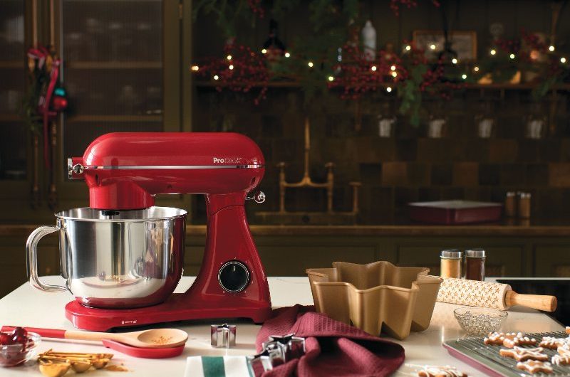 Christmas kitchen island with a red stand mixer, festive decorations, with a run of cabinetry behind it.