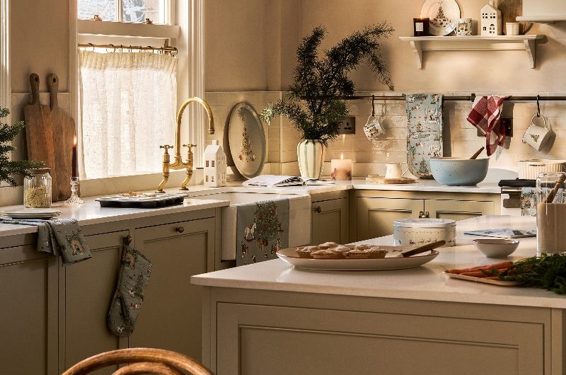 A chic, neutral scheme with zellige tiles, Shaker cabinetry, open shelving, a window with a cafe curtain, and festive decor.