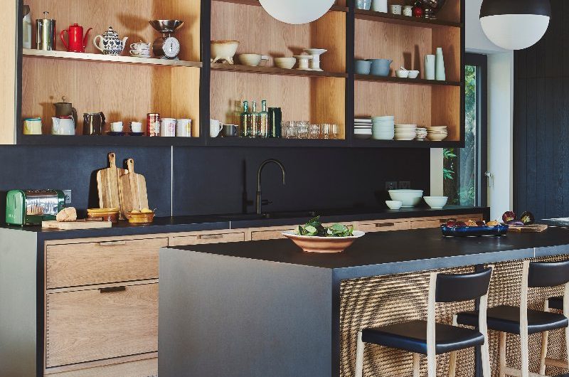 Wood drenched kitchen with dark work surfaces, matt black finishes, and industrial-style accents.