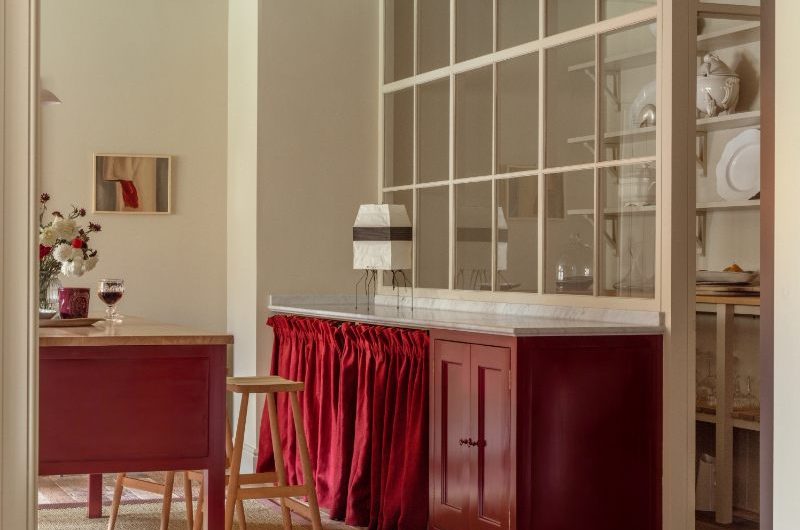 A warm and cosy kitchen trend with a walk-in pantry, red cabinetry and a matching freestanding island.
