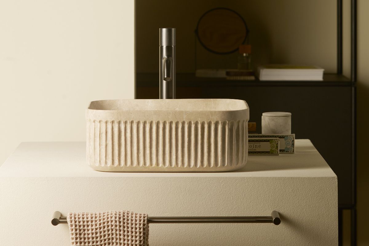 A neutral, fluted countertop basin on a concrete-effect stand, with a nickel finish tap, and matching towel holder.