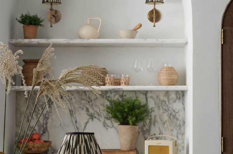 A stylish kitchen design with rechargeable wall lights, marble surfaces, and dark cabinets.