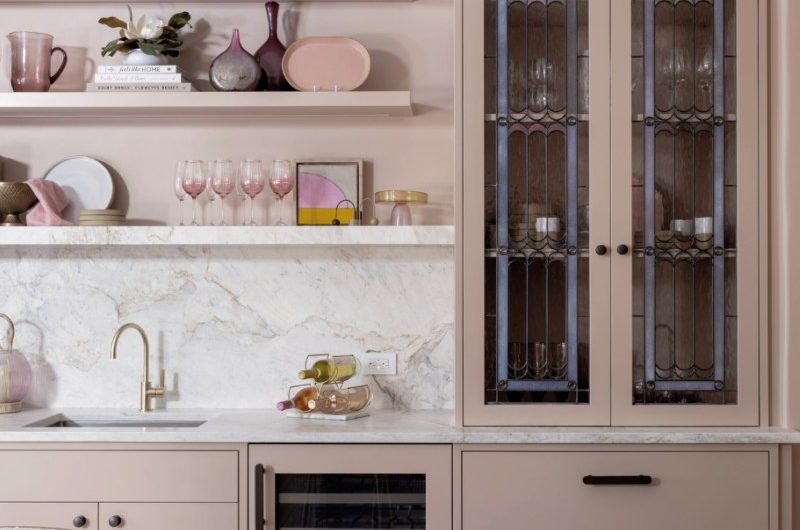 A restaurant-inspired kitchen with open shelving, an elegant dresser, marble surfaces, and brass details.