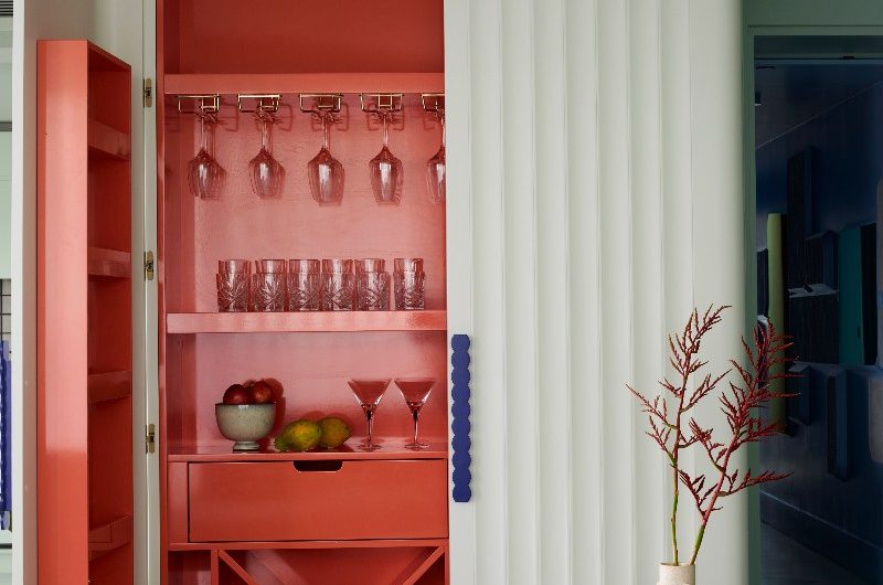 A home bar with bright red interiors, fluted sage green exterior and dark blue scalloped handles.