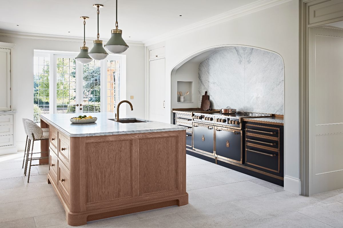 A mixed style kitchen design with a wood island and a statement cooking zone with painted steel units and range and a hidden extractor.