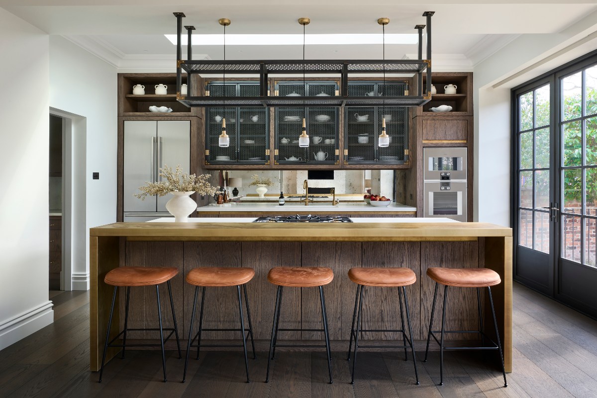 A modern kitchen design with dark wood cabinetry, a central island with a brass breakfast bar, and industrial finishes.