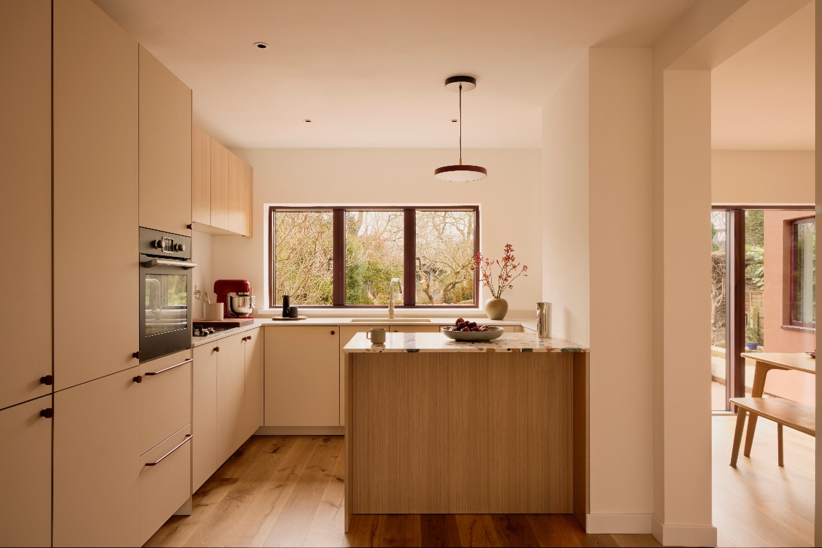 Pastel kitchen with minimalist cabinetry and neat worktops, flooded with natural lighting.