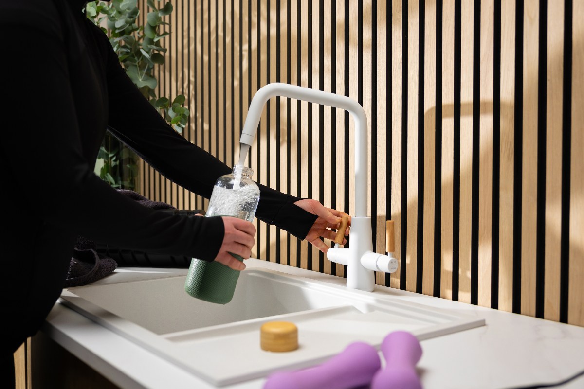 A Scandi kitchen with wood panelling, a white sink, and white four-in-one water tap.