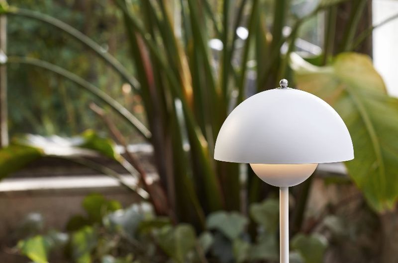 An outdoor area with a dark marble table, white table lamp, and greenery.