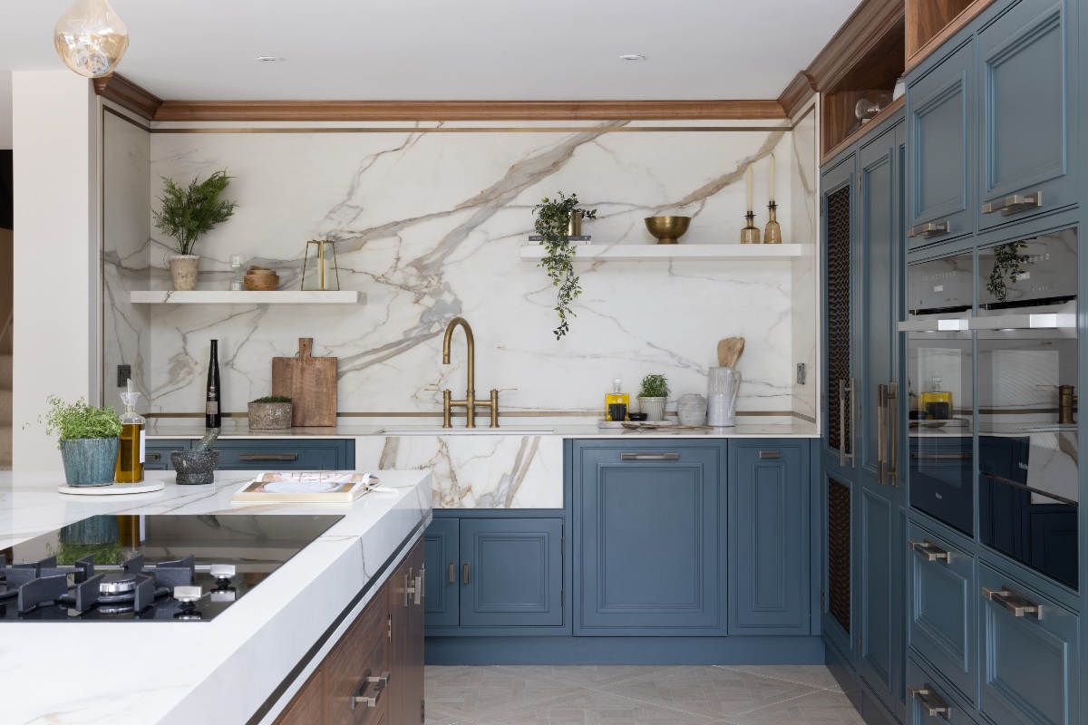 A sink zone with veiny porcelain surfaces and open shelving sits close to the preparation and cooking area on the island.