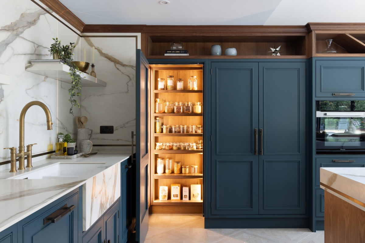 A contemporary kitchen design with dark blue cabinetry and an illuminated corner pantry cupboard.