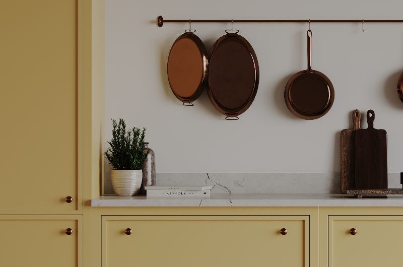 A run of cabinetry painted in yellow with slim frames and copper knobs.