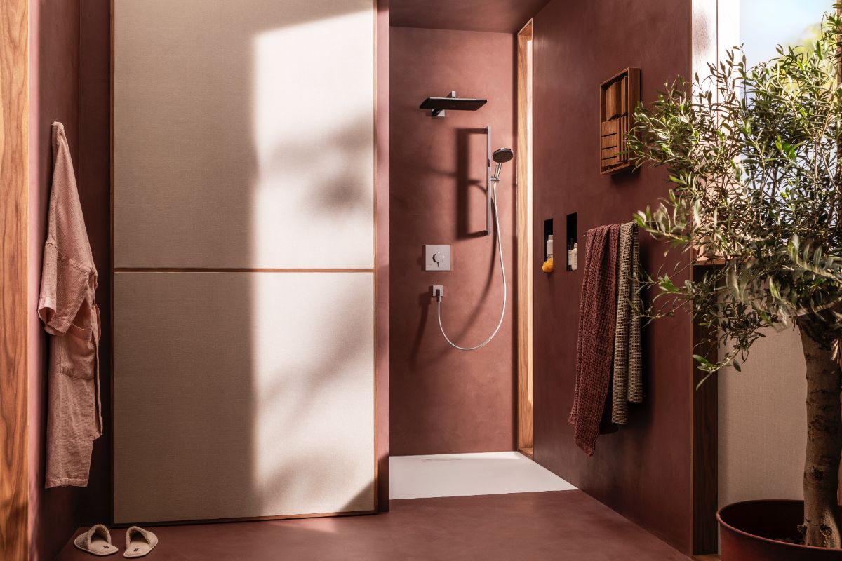 A terracotta-coloured showering space with a wall-mounted system, and house plants.