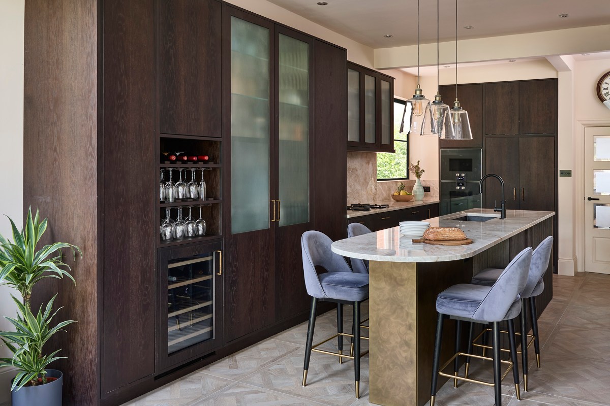 A dark wood kitchen design with a restaurant-inspired interior design, a central island with a breakfast bar, and a drinks zone.