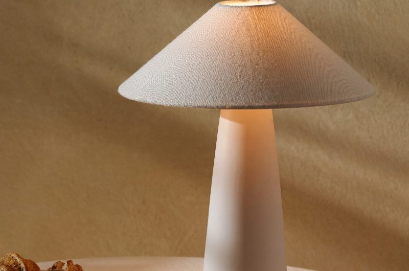 A neutral interior scheme with a round table with linen table cloth, warm lighting, and minimalist decor.