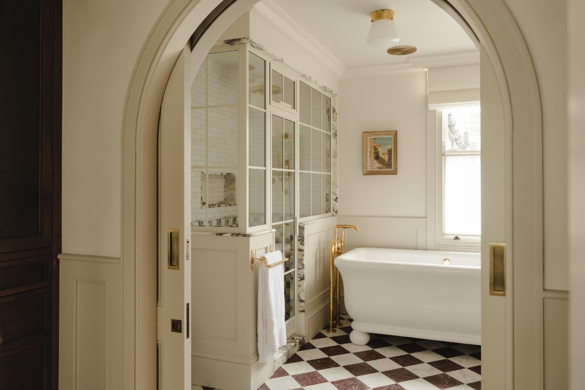 A large bathroom design with a conservatory-style shower, freestanding bath, and checkerboard flooring.