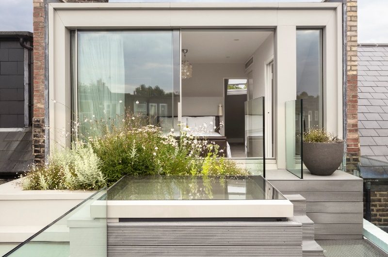 A loft conversion maximising views in the sleep space, with glass sliding doors and greenery.