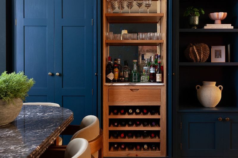A dark blue kitchen design with an adjoining dining area and drinks cupboard which can be tucked away with pocket doors.