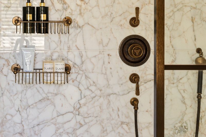 A statement shower design with bronze brassware and veiny wall and floor surfaces.