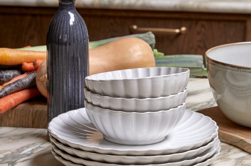 Closeup at the kitchen island with reeded crockery, and salad vegetables spread out.