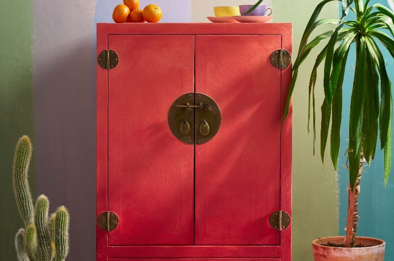 A colourful scheme with a red cupboard, with patterned flooring, and striped backdrop.