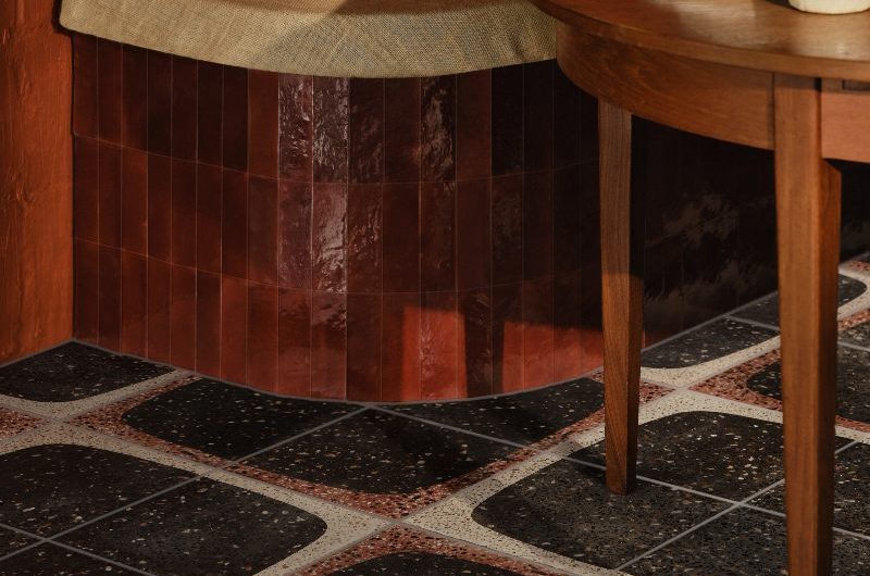 A warm dining room with speckled flooring, bench seating, and a wood table.