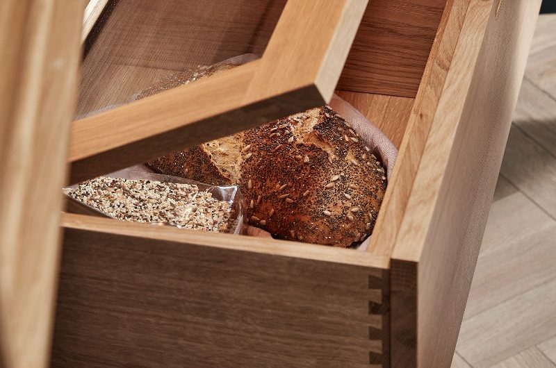 Closeup at a pantry design with an integrated bread bine with clear glass lid.