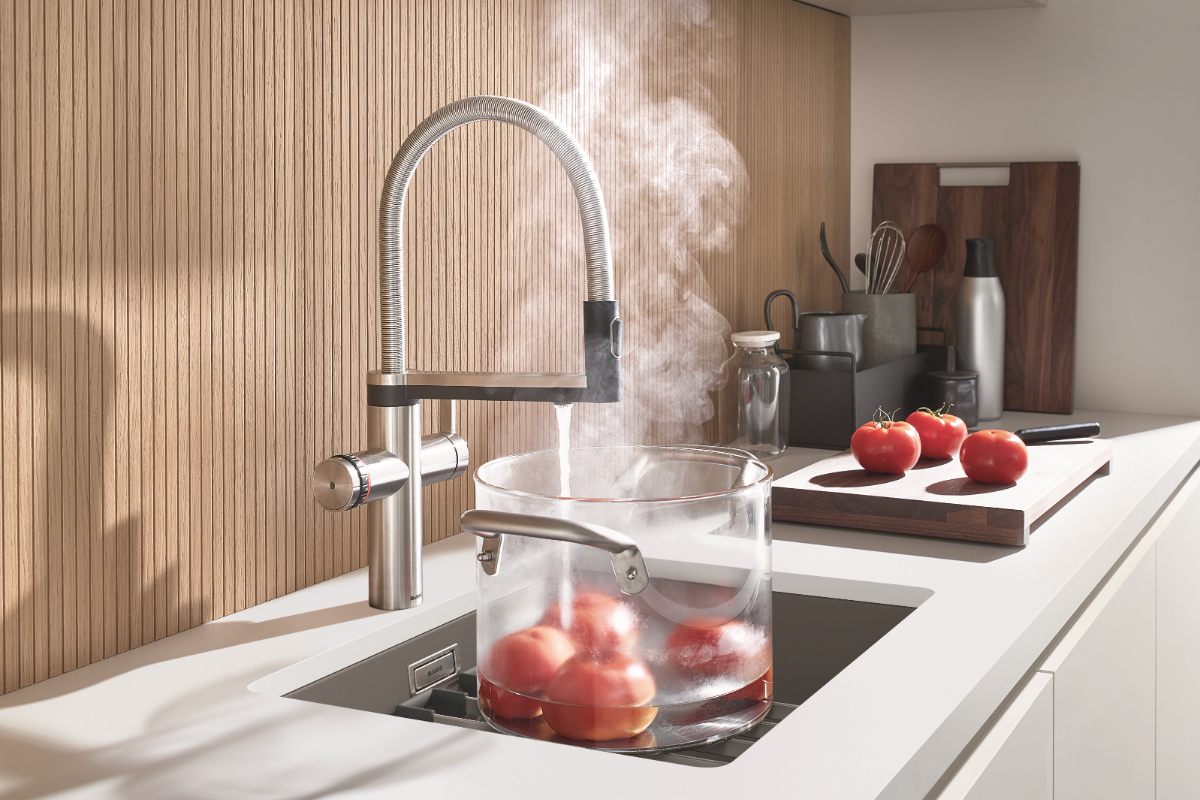 A Scandi scheme with white furniture, matching white worktop, reeded wood splashback, with a stainless steel inset sink and a boiling-water tap.