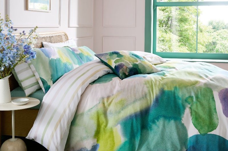 Colourful scheme with green and blue bed linen, rattan rug, and timeless wall panelling.
