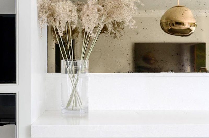 An interior design project with white cabinetry, mirror splashback and metallic handles.