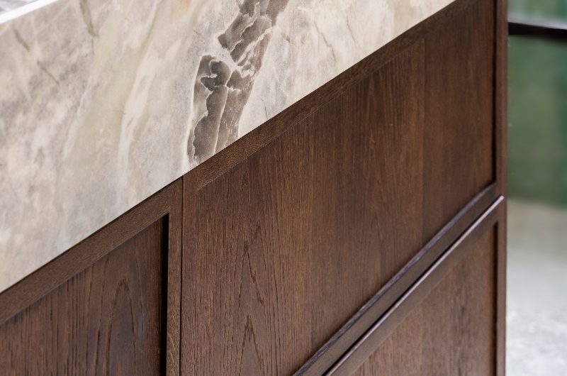 Closeup at the wood vanity unit and its stone countertop.
