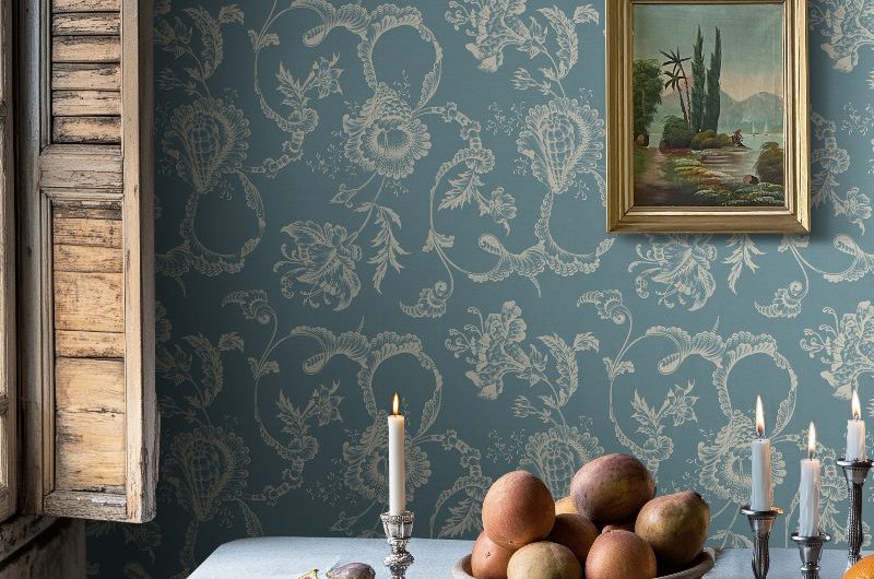 Closeup at a rustic, elegant dining room with wall art, a wood table with a chunky linen cloth, and vintage candlesticks.