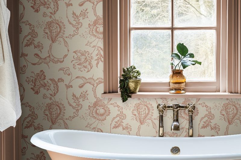 A blush bathroom design with a painted tub, painted woodwork, and brass bath filler.