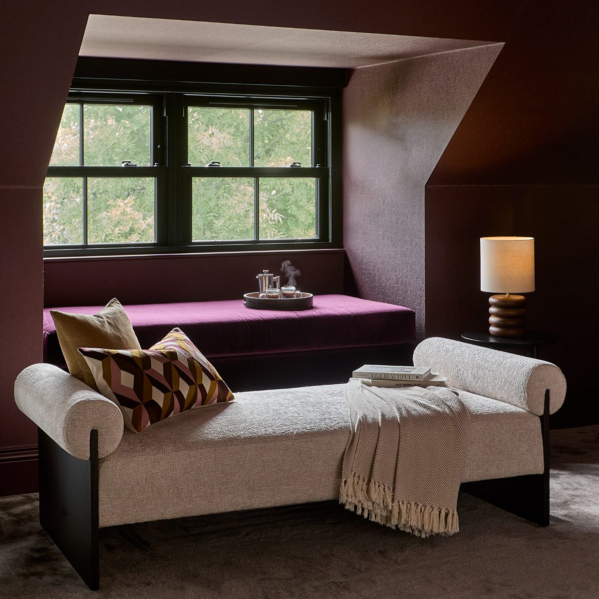 Dark and moody scheme with a natural fabric day bed bench and mood lighting.