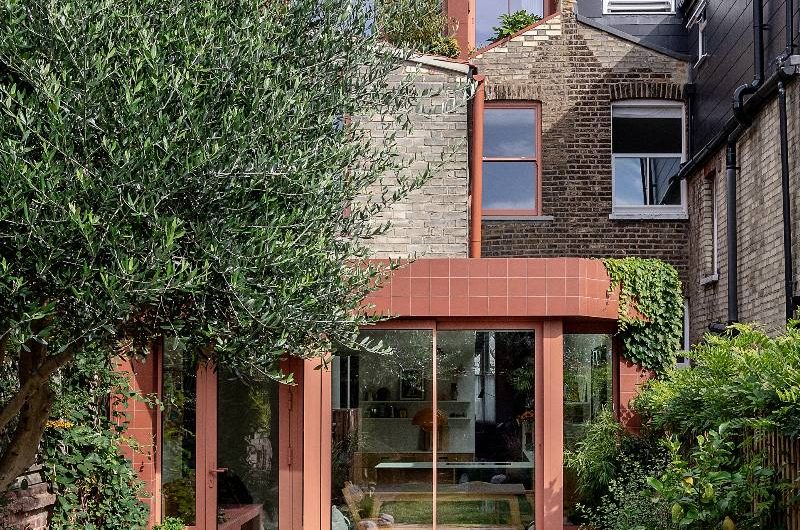 View of a kitchen extension with peach-coloured glazing and matching tiles.