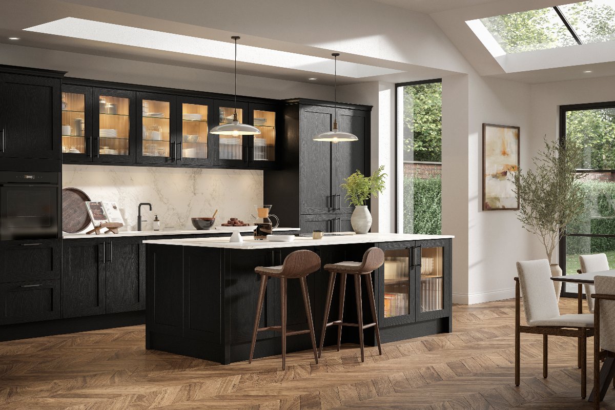 A black kitchen design with a matching island with seating, fluted glass, and warm wood flooring.
