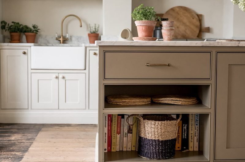 A neutral kitchen design with a classic cabinetry, central island, wood flooring, and a patterned rug.