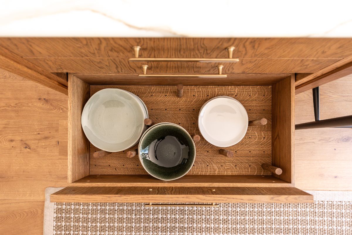 View inside a drawer with a peg board holding plates and bowls.